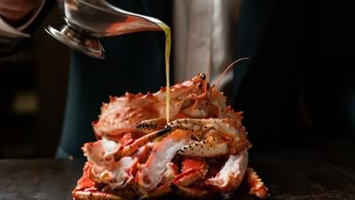 pouring sauce over cooked crab