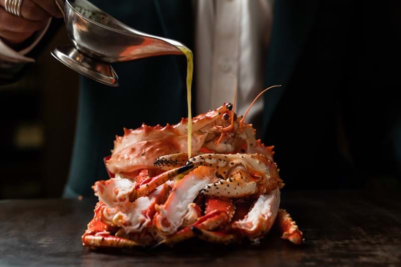 pouring sauce over cooked crab