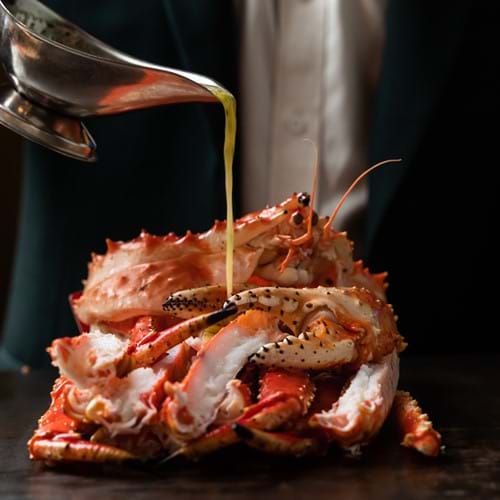 pouring sauce over cooked crab