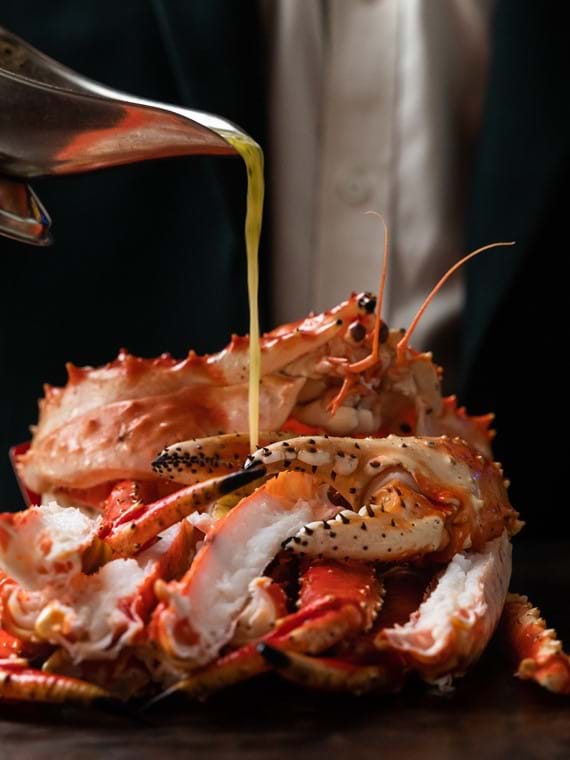 pouring sauce over cooked crab